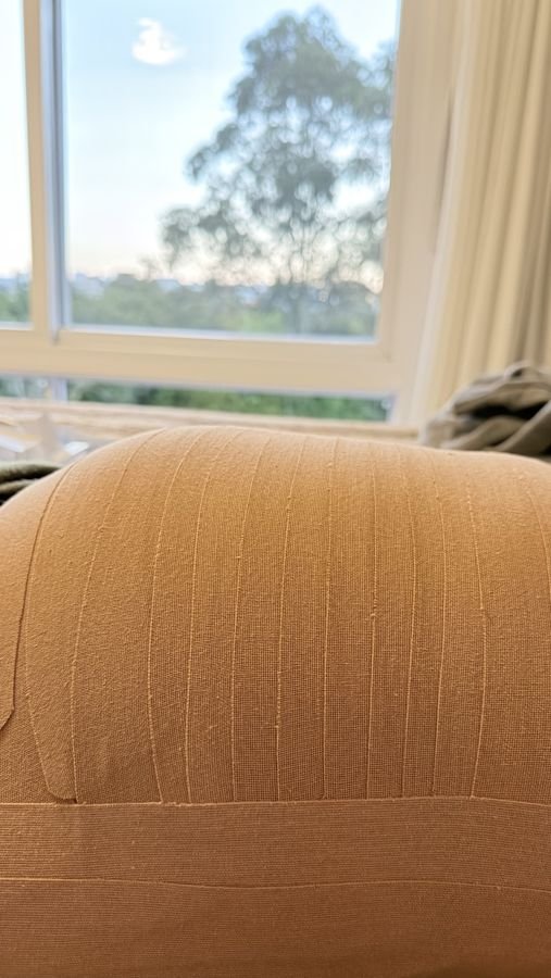 Abdômen com bandagem elástica terapêutica no pós-parto, ao lado de uma janela